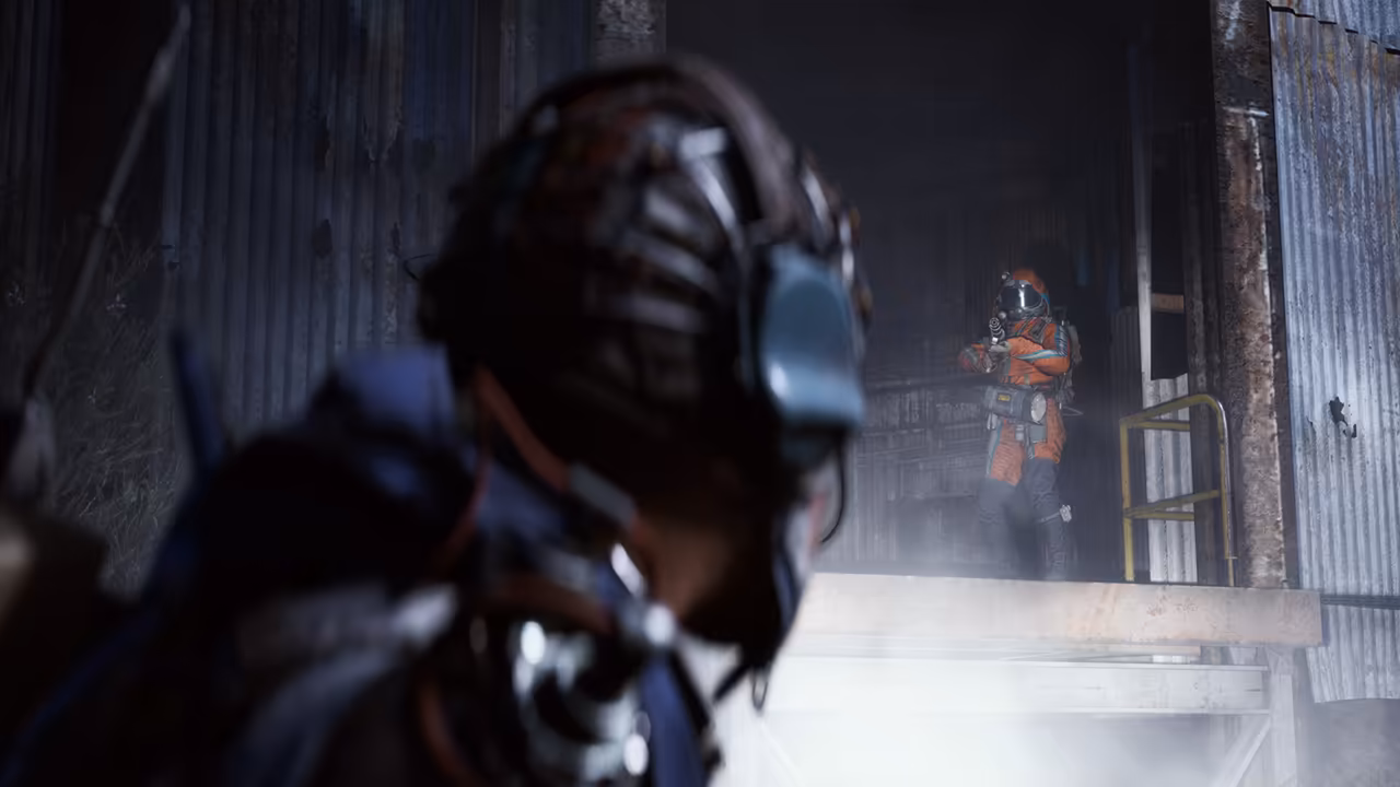 A close, blurred helmeted head at left; a figure in an orange jacket stands in a bright doorway at the back of a metal building.