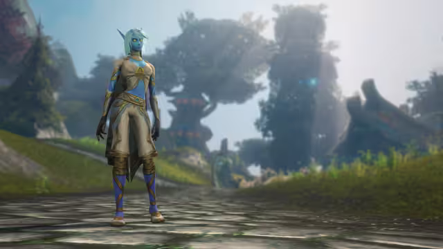 A blue-skinned woman with long pointed ears, glowing yellow eyes and short pale teal hair stands on a worn stone path in a cream and gold top and breeches, a dark short cape and purple leggings wrapped with gold bands. The blurred background shows huge trees, a building with a curved roof and sunlight breaking through haze.