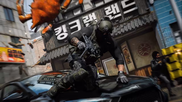 A soldier in a helmet and gloves leaps over a black car's hood with a rifle; behind him a storefront carries large Korean letters, an orange crab figure tumbles from above and another armed figure stands at right.