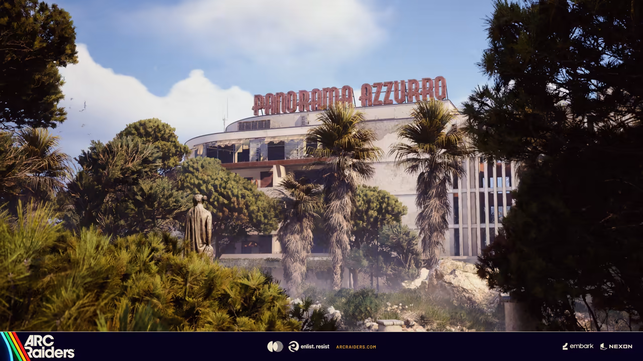 A long white hotel with red rooftop letters behind overgrown gardens and a statue.