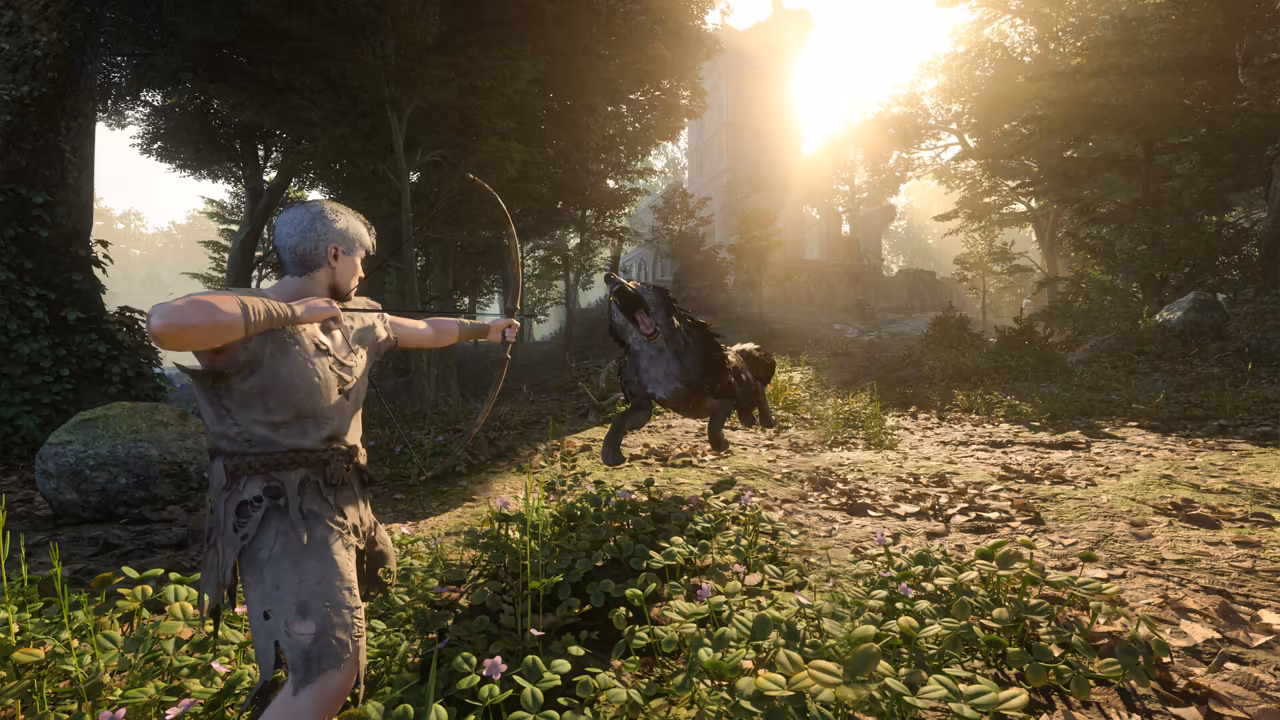 A sunlit forest of tall trees and clover. At left a man with short gray hair, dressed in torn, patched linen, draws a simple wooden bow. A large dark wolf with bared teeth leaps toward him from the path ahead, and the ruins of a stone tower glow in bright sunlight beyond the trees. No game interface is shown.