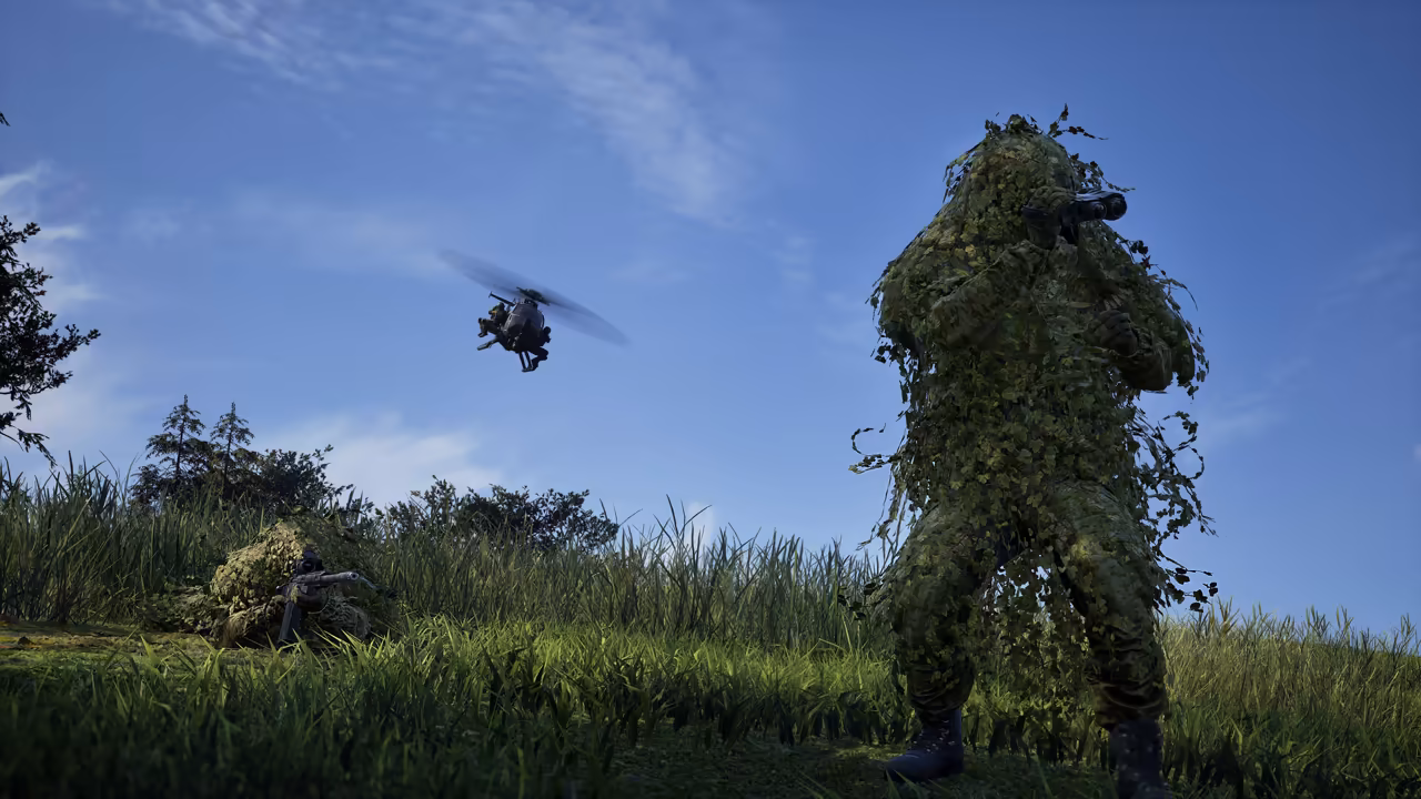 A figure in a dense green ghillie suit holds a rifle in a sunny meadow; another lies hidden in the grass at left and a small helicopter flies across a blue sky.