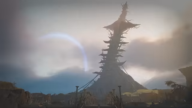 A gigantic, gnarled tower like a dead tree trunk ringed with jutting platforms rises from a conical hill, tied by ropes to posts below, beyond a wall of wooden poles, with a pale arc of light across a hazy, cloudy sky.