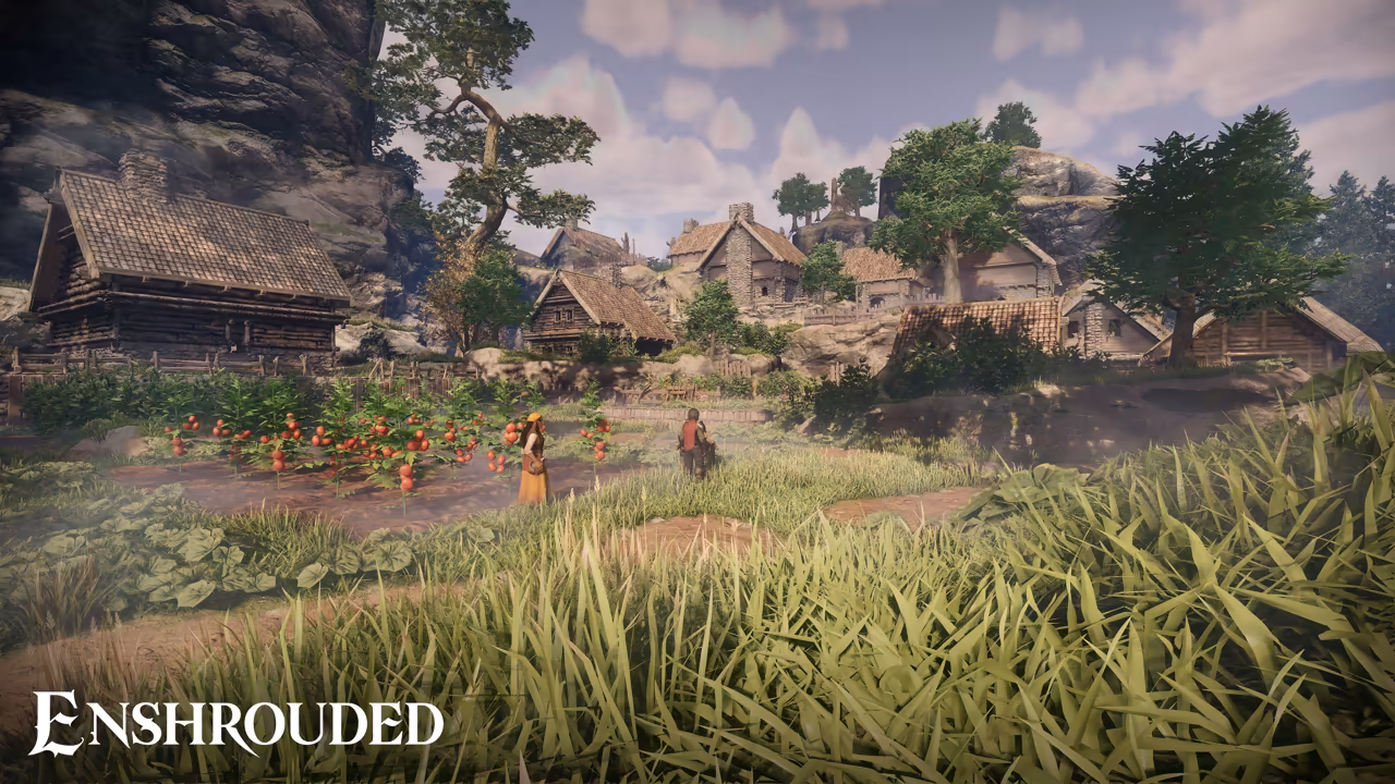 Tall grass in the foreground leads to a garden of leafy plants heavy with red fruit, where two people in simple clothes stand. Behind them a village of wooden and stone houses with thatched roofs sits among green trees under a gray cliff and a blue sky with soft clouds. The Enshrouded logo is at bottom left.