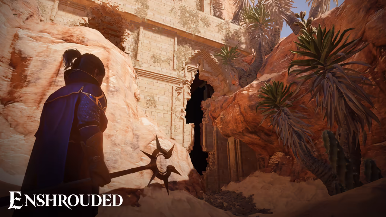 Warm desert light on red and orange rock. At left a dark-haired figure in a high-collared blue cloak with gold trim holds a staff topped with sharp spikes. Ahead a carved sandstone temple wall has a jagged dark hole broken through it, and spiky desert palms and cactus-like plants grow from the rocks. The Enshrouded logo is at bottom left.
