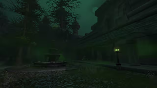 A two-tiered stone fountain on an octagonal base sits in a weedy courtyard of broken cobbles, beneath tall, sparse pines and a spired tower. To the right a long stone building with a sloping roof runs beside a walkway where a lamp post gives off green light under a dark green sky.