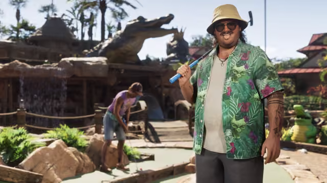 A heavyset, grinning man in a bucket hat, sunglasses and a green tropical-print shirt holds a golf putter over his shoulder on a mini golf course with a waterfall and a giant alligator statue, as a woman lines up a putt behind him.