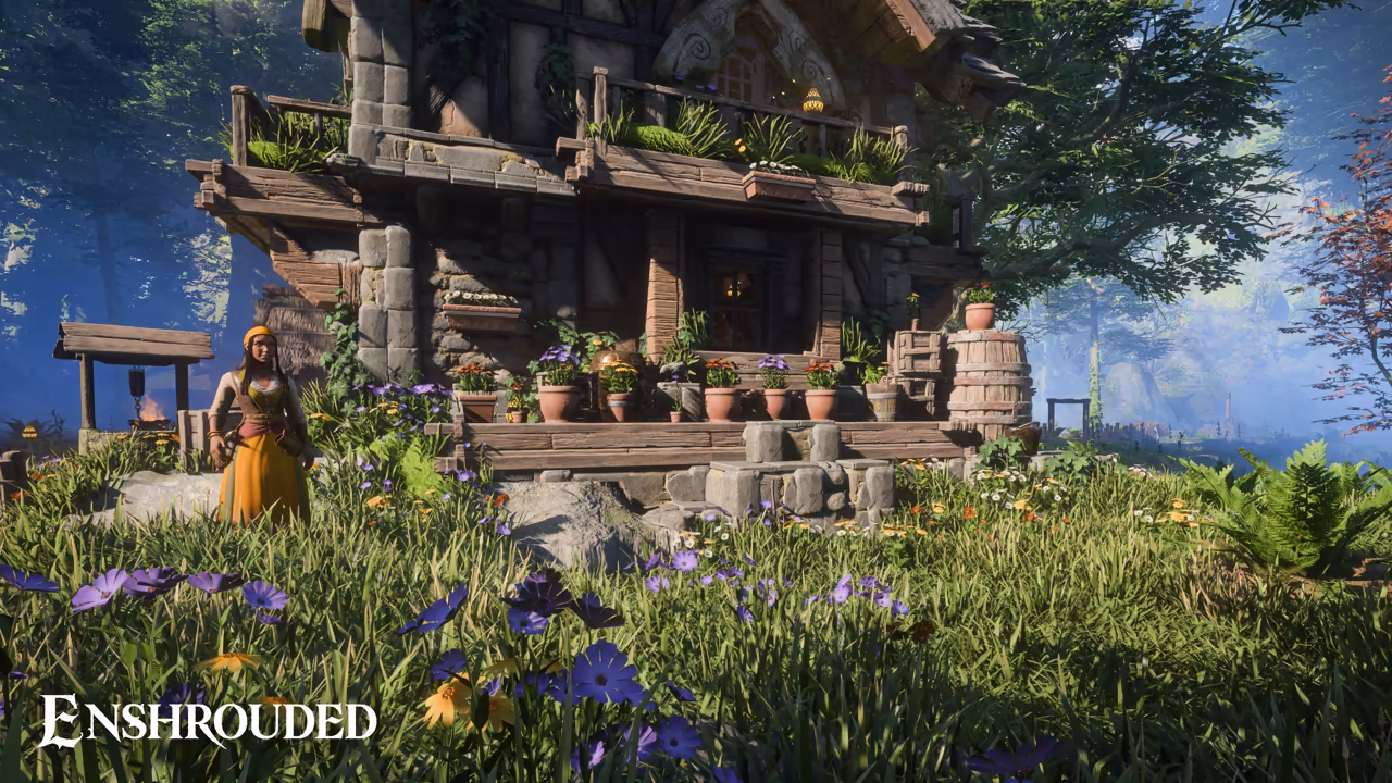 Bright forest daylight. At left a woman with long hair in a yellow dress stands in tall grass and purple flowers. Beside her stands a two-story house of stone and dark timber with a balcony of plants, a wooden porch lined with clay pots and flowers, and a barrel. Trees and a well stand behind. The Enshrouded logo is at bottom left.