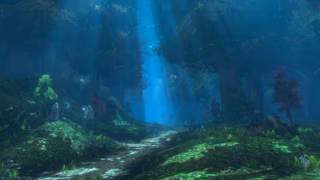 A worn cobbled path winds through a dim blue-green forest of huge trees, where a single broad beam of light breaks through the canopy into the mist. Pale carved stones and small glowing lamps stand on the mossy slopes, with purple-leaved trees on either side.