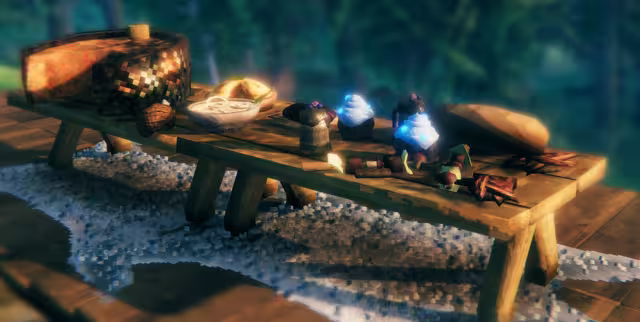 A wooden table on a stone floor set with a loaf of bread, a bowl, two blue frosty desserts in cups, cooked meat and other dishes.