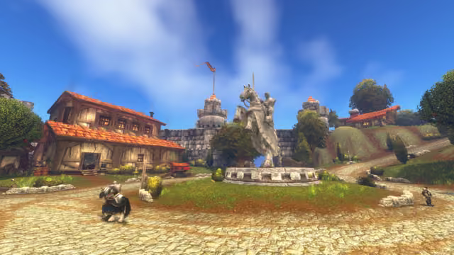 A large pale statue of an armored rider raising a sword on a rearing horse stands on a round plinth in a grassy square. Behind it are a stone wall with two round towers and a pennant, timber-framed houses with orange tiled roofs and a hillside road, while a rider in armor on a horse and a soldier stand on the cobbles in front.