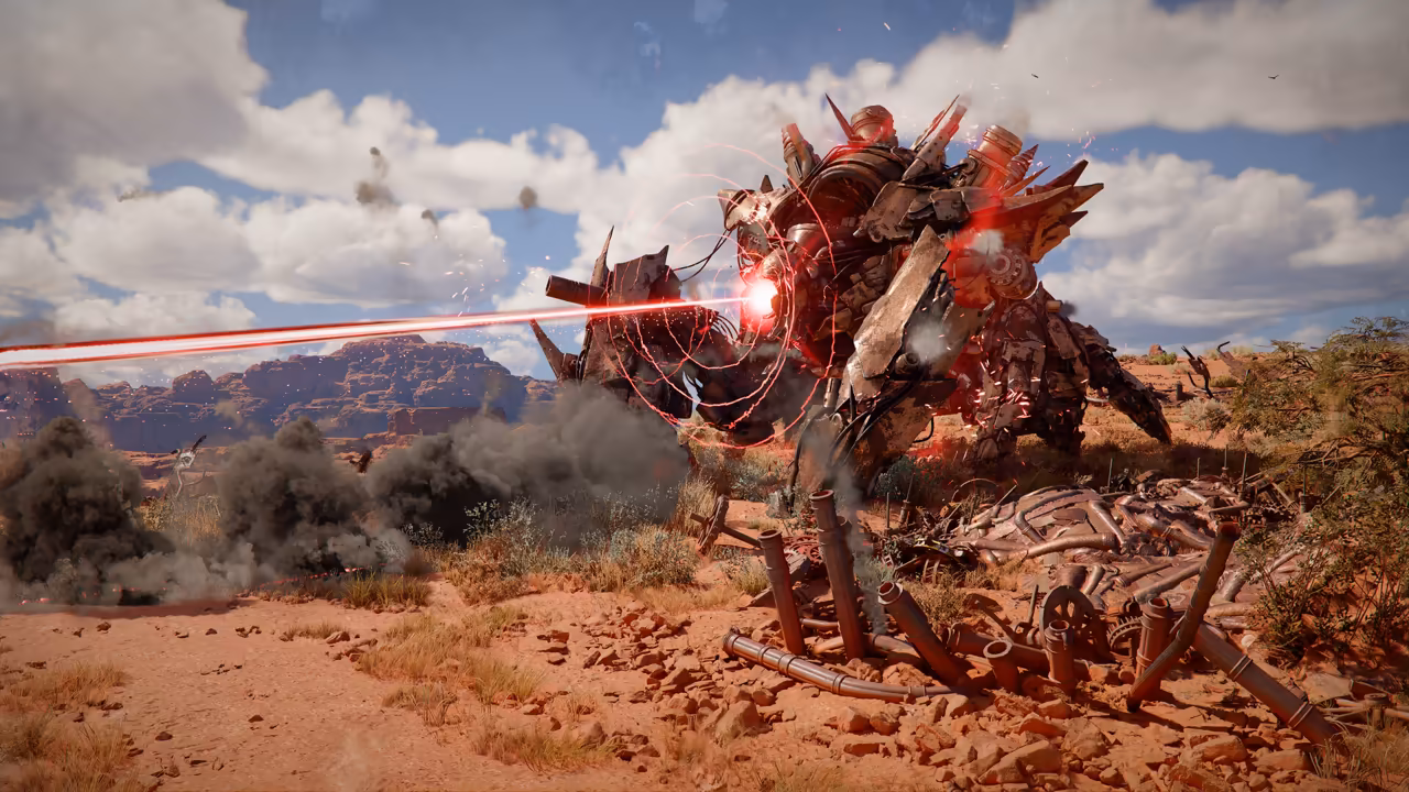 On a dry plain of red earth and scrub under a blue sky with white clouds, a huge rusted machine on crab-like legs, studded with spikes and pipes, shoots a bright red beam from its front. Dark smoke rises around it, and twisted metal wreckage lies on the ground. Red mesas line the horizon.