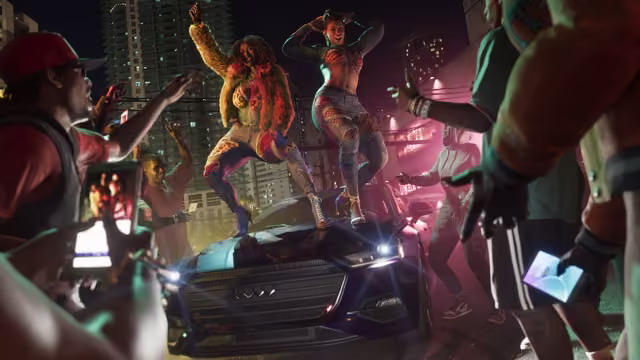 At night among high-rise towers, two women in bold outfits dance on the roof and hood of a dark sedan with its headlights on, while the crowd around them cheers and films on smartphones under pink light.