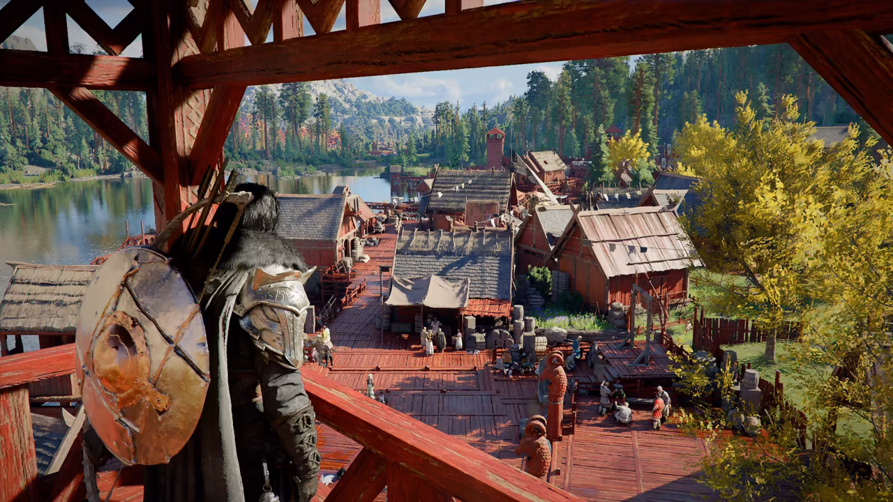 Seen from behind, a man in dark armor with a large round shield and a quiver of arrows stands on a red-painted wooden balcony. Below lies a town of red timber houses with shingle roofs, a market square of stalls and people, and a lake bordered by pine forest and a yellow-leaved tree.