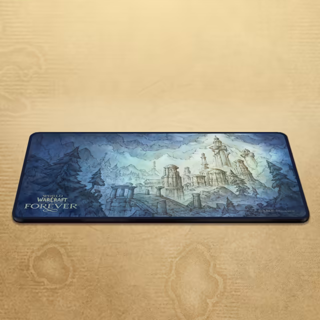 A long desk mat lies on a parchment-textured surface. Its blue, sketch-like artwork shows pale domed towers, columns and stone arches rising among pine trees and swirling clouds, with the World of Warcraft Forever logo in the lower left corner.