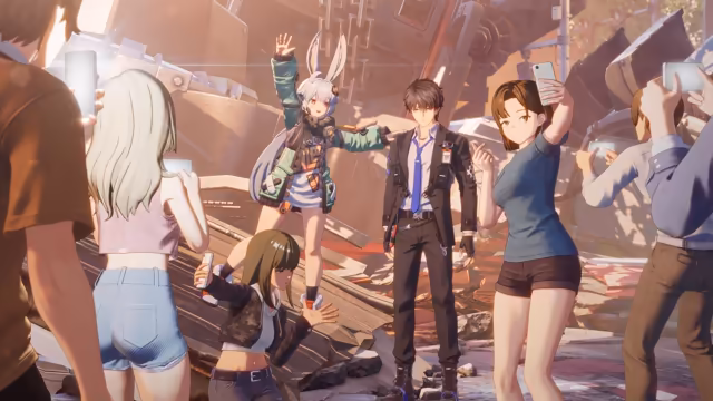 Warm sunlight over a pile of wrecked metal machinery: a girl with long white hair, rabbit ears and a green jacket raises one hand, a dark-haired man in a black suit, white shirt and blue tie stands beside her, a crouching girl in a camouflage jacket and a woman in a gray T-shirt pose for selfies, and onlookers in the foreground hold up phones. No game interface is shown.