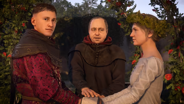 Three figures before a hedge of red roses: a young man in a patterned crimson coat and dark hood, a balding priest in a brown habit with a red collar, and a woman in a white dress and green leaf wreath; their hands are joined.