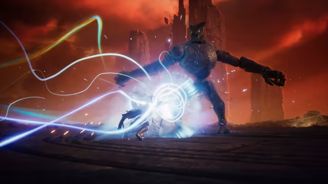 On a dark stone floor beneath a blood-red sky and tall rock pillars, a small figure in pale clothing strikes at a huge armored stone giant whose head is a carved owl with yellow eyes and whose long arms spread wide; ribbons of blue, white and gold light whirl around the figure and burst against the giant.