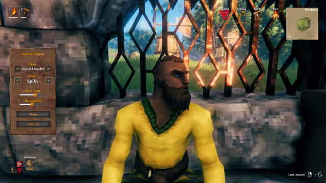 In-game screenshot of a bearded Viking in a yellow tunic seated before a lattice window, with a menu on the left listing hair, beard, hair tone and blondness options.