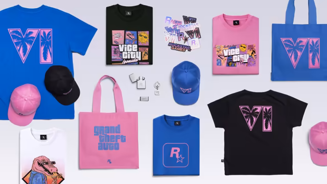 Merchandise laid flat on a pale gray surface: blue, black and pink T-shirts printed with the game's palm-tree logo, Vice City comic art or the Rockstar logo, a white shirt with a pink alligator in sunglasses, pink, black and blue caps, a pink tote bag reading Grand Theft Auto and a blue one with the palm-tree logo, a sheet of Rockstar stickers, and a chrome lighter, keychain and money clip.