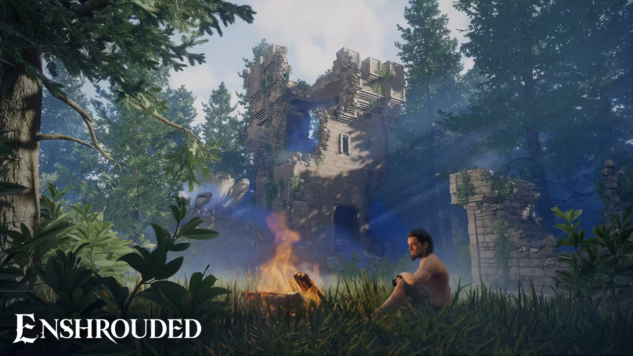 A sunny forest clearing with tall trees and ferns. At right a dark-haired, shirtless man sits in the grass with his knees up beside a small campfire. Behind him rise the broken walls of an old stone tower overgrown with ivy, and another ruined wall stands at right. The Enshrouded logo is at bottom left.