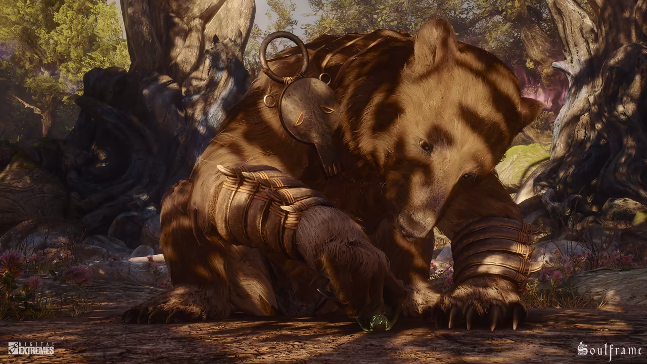 Sunlight falls in patches through the trees onto a giant brown bear crouched low on a forest floor among gnarled roots and pink flowers. A big iron ring with a carved metal disc hangs from its neck, and its forelegs are wrapped in bands of wood and rope. With one clawed paw it touches a small round object glowing green on the ground. Digital Extremes' logo sits in the lower left corner and the Soulframe logo in the lower right.