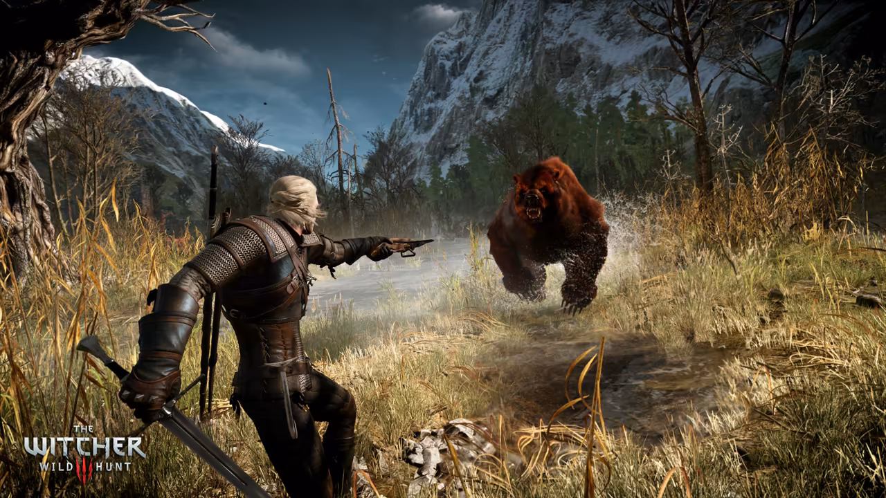 A white-haired man in armor with a sword in his lowered right hand points a hand crossbow with his left at a large brown bear splashing toward him across shallow water. Bare trees, golden grass and snowy cliffs frame the scene, and The Witcher Wild Hunt logo sits at lower left.