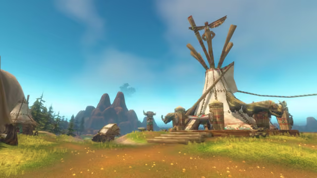 A tall cream tent stitched with brown thongs, with long carved poles and a carved bird at the top, stands on a wooden platform with log steps, flanked by the mounted heads of horned beasts and painted posts. Smaller tents, a horned totem, pines and red rocky peaks sit to the left, and a hazy tree-covered shape hangs in the sky above the peaks.