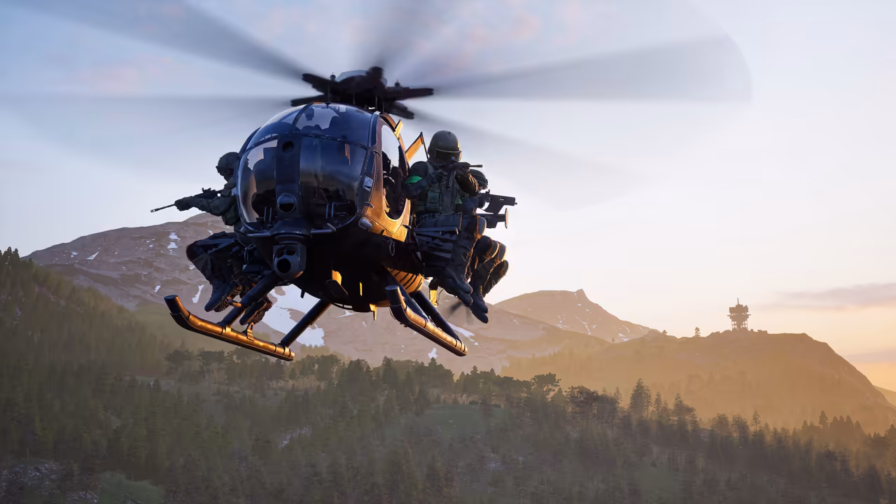 A light helicopter with orange skids banks toward the camera, two armed soldiers seated on each side outside the cabin; snowy peaks and a tower on a far hilltop sit under a pale evening sky.