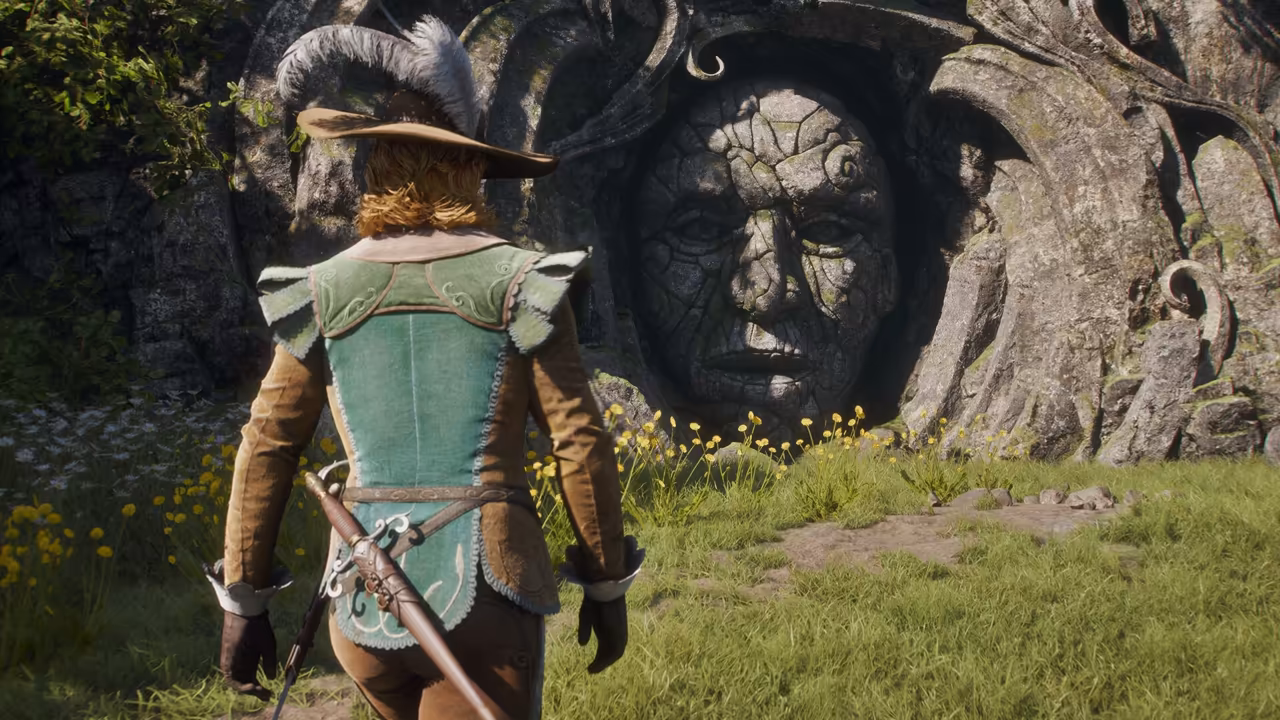 Seen from behind, a figure with ginger hair under a broad brown hat with large gray feathers wears a pale green embroidered waistcoat over brown sleeves, a slim sword with a basket hilt at the hip. Ahead, a huge weathered human face is carved into a cliff of mossy rock framed by curling stone shapes. Yellow wildflowers and green grass fill the foreground. No game interface is shown.
