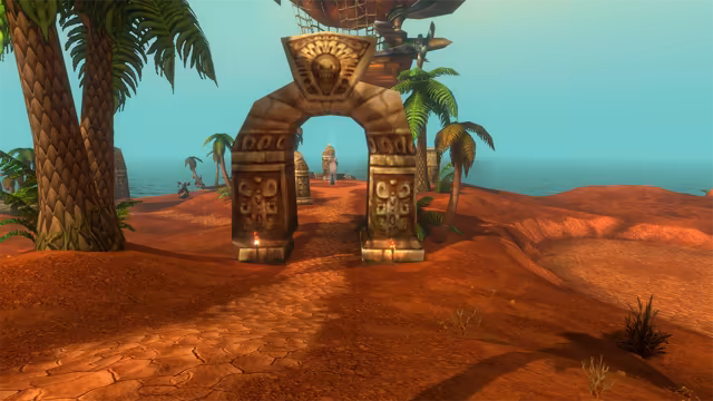A stone archway with carved spiral panels and a grinning face at its top stands on a path of cracked red earth, with a small torch burning at the foot of each pillar. Palm trees rise on both sides, carved stone pillars stand further along the path toward the sea, and the wooden gondola and propeller of an airship hang just above the arch.