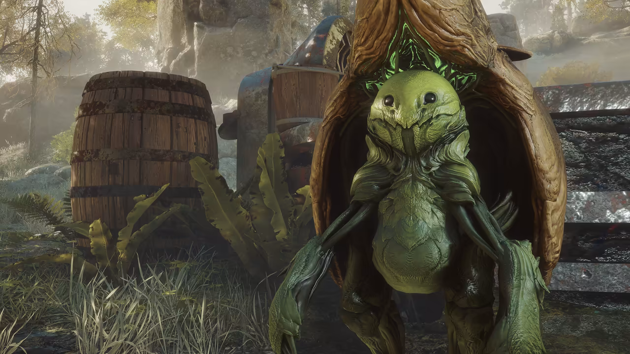 Close view of a pale green creature with a rounded head, two small black eyes, a ridged belly and long, thin, jointed limbs, standing in the opening of a tall brown pod shaped like a split husk, its inner wall laced with bright green glowing veins. Old wooden barrels and broad leaves sit to its left, and rocks and trees fill the sunlit background. No game interface is shown.