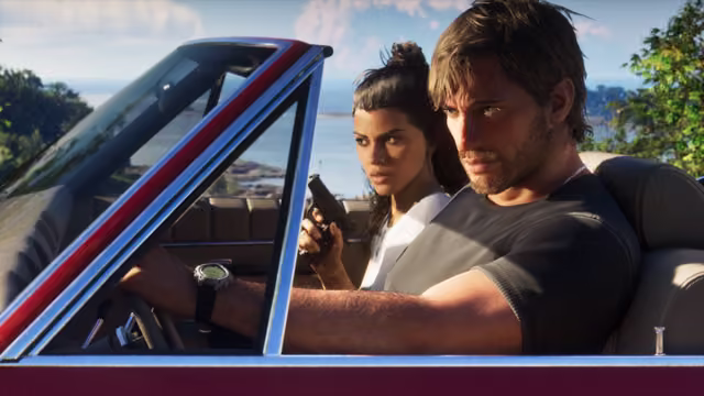 A man with tousled hair and a stubbled face drives a vintage red convertible, one hand on the wheel, while a woman with her hair in a bun sits beside him holding a pistol, with trees and a bay behind them.