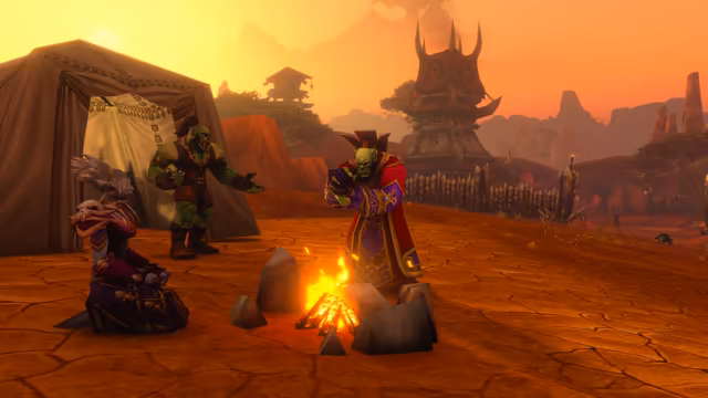 On cracked red ground, an orc in red, purple and gold robes with a tall collar stands over a campfire ringed with stones, another orc in brown leathers gestures beside a dark canvas tent, and a long-eared figure with white hair in a purple robe trimmed with skulls kneels nearby. Behind them are a wooden palisade, a spiked tower hung with red banners and red rock canyons under an orange sky.