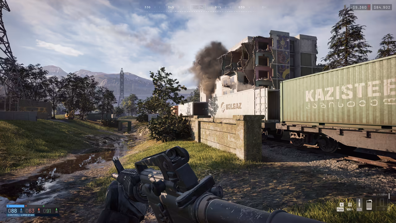 First-person view over a carbine's sights across a grassy rail yard; green and white shipping containers on a train at right, a smoking, half-destroyed apartment block beyond, and Control: Lonestar on the score panel.